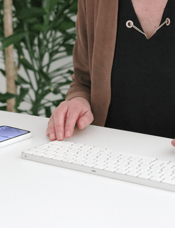 Susanne sitter vid ett skrivbord med mobil och tangentbord
